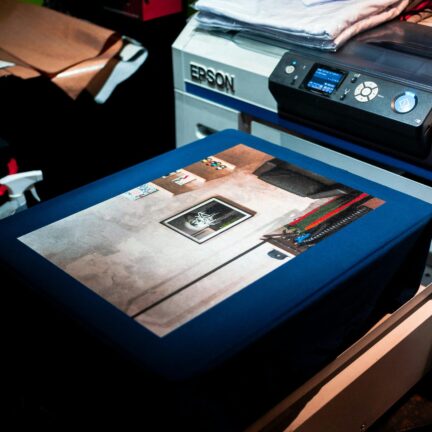 Close-up of a professional printer printing a custom artwork design on fabric in a studio setting.