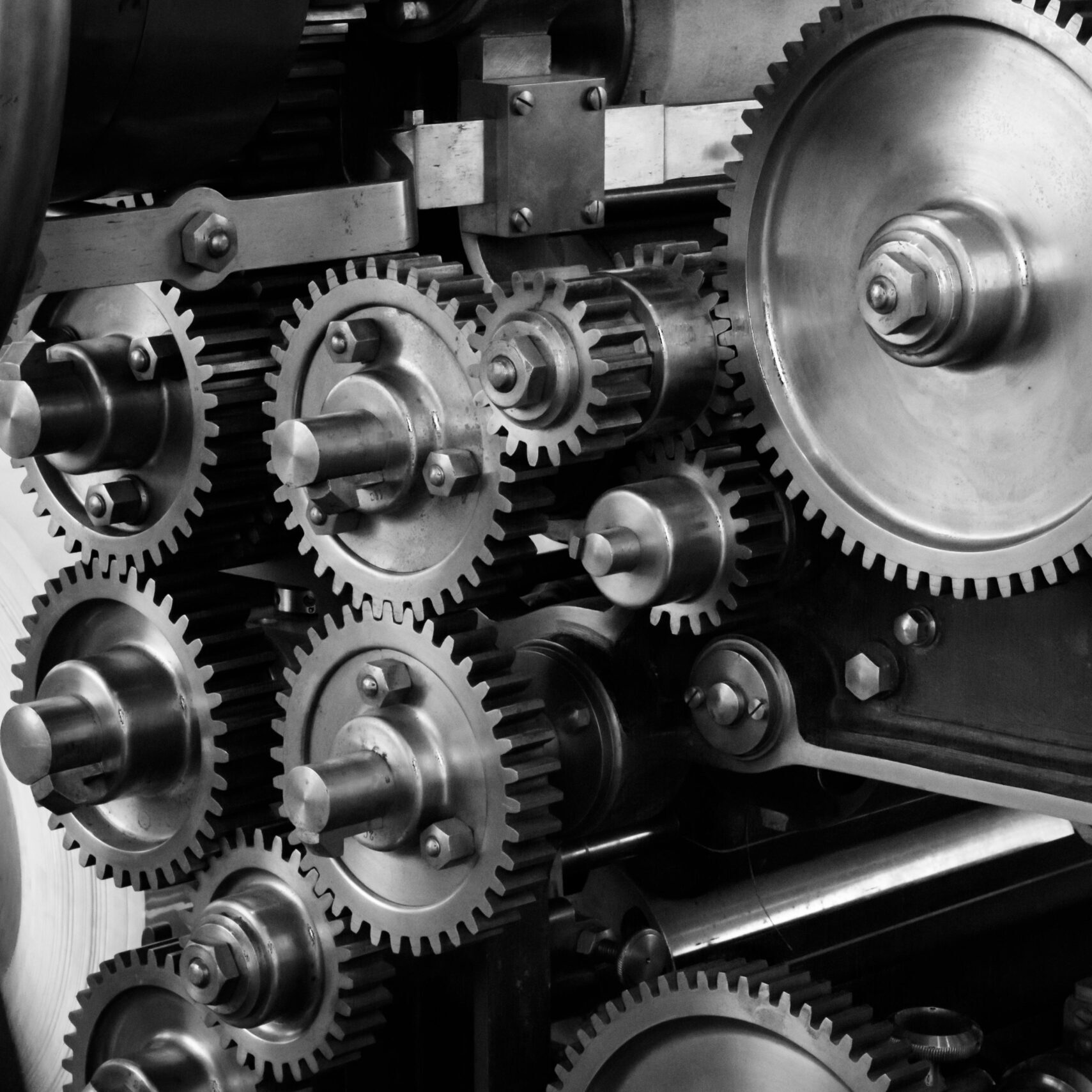 Close-up view of a complex industrial gear mechanism in black and white.